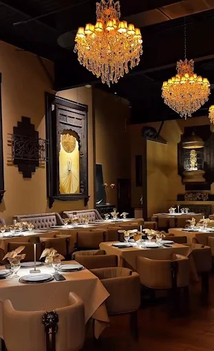 Qalandar Quisine dining room with low chandelier light and set tables.
